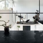 Ambiente con pavimento nero lucido, isola scura e vetrata sul giardino