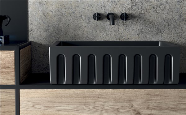 Lavabo nero a superficie scanalata con miscelatore a parete su mobile in legno