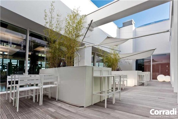 Terrazza con pergola a lamelle, tavolo da pranzo e vista sul giardino