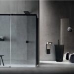 Box doccia con anta scorrevole e profili neri in un bagno effetto cemento