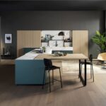 Cucina con isola blu, tavolo integrato e colonne in finitura legno
