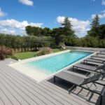 Piscina esterna con pedana in materiale composito effetto legno e lettini