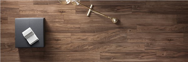 Dettaglio di pavimento in gres effetto legno dai toni caldi con complementi
