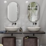 Bagno con due lavabi d'appoggio su mensola, specchi ovali e mobili tondi