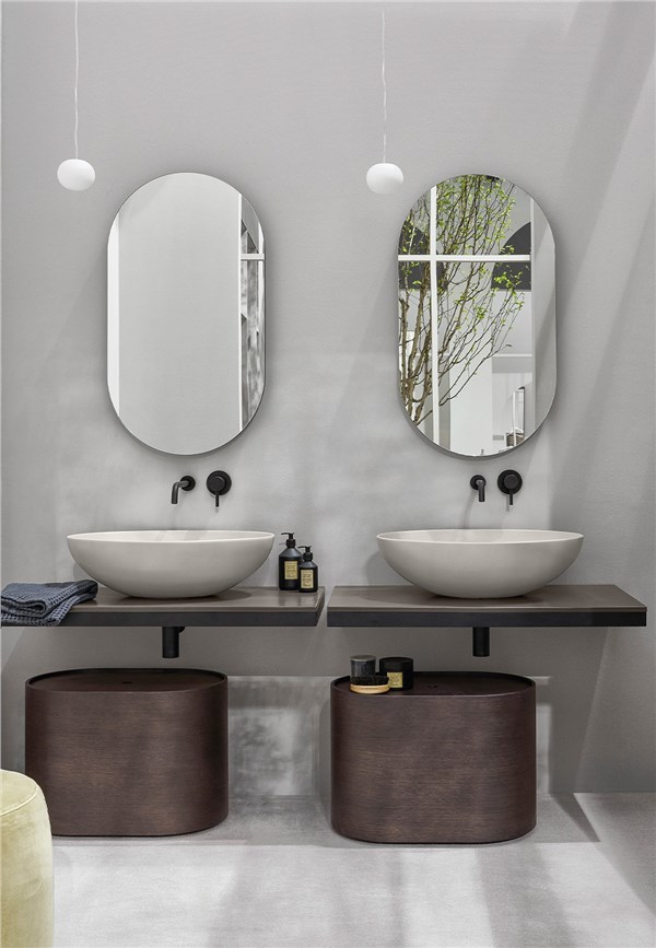 Bagno con due lavabi d'appoggio su mensola, specchi ovali e mobili tondi