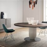 Tavolo ellittico con base centrale e sedie verdi in una sala da pranzo