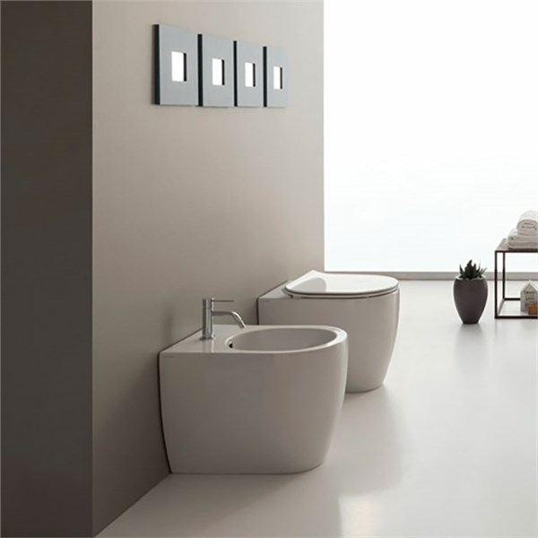 Vaso e bidet sospesi bianchi in un bagno minimale con placche di comando