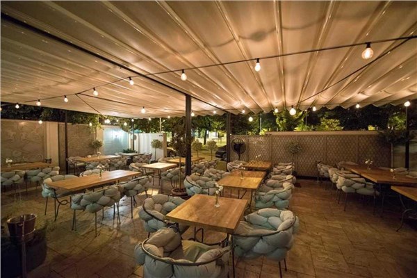 Ristorante all'aperto con copertura in legno a lamelle, tavoli e luci sospese