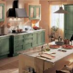 Cucina rustica verde con ante a telaio, cappa e tavolo in legno