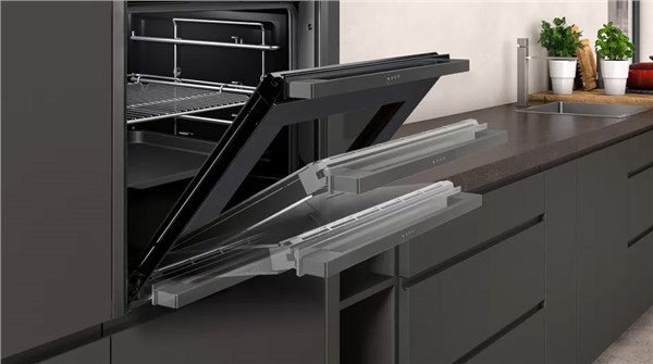 Forno da incasso con porta a scomparsa aperta in una cucina scura