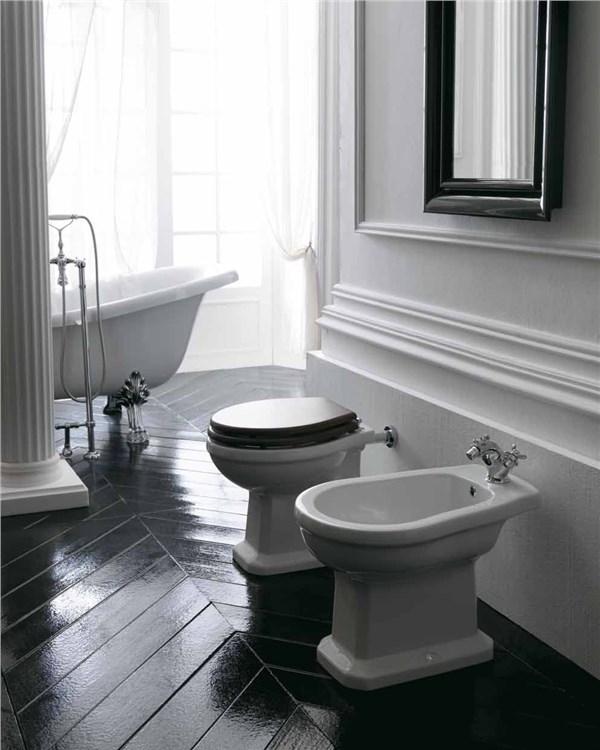 Bagno in stile classico con vaso e bidet a terra, vasca e pavimento scuro