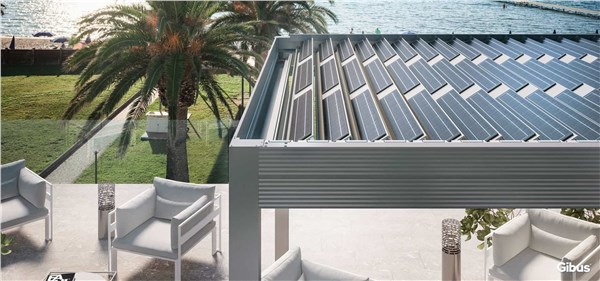 Pergola bioclimatica con lamelle fotovoltaiche sopra una zona relax con palme
