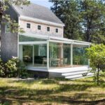 Veranda vetrata addossata a una casa in legno immersa nel verde