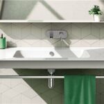 Lavabo sospeso bianco su parete rivestita in piastrelle esagonali verdi