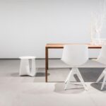 Ambiente minimale con pavimento e parete in resina continua chiara e tavolo bianco