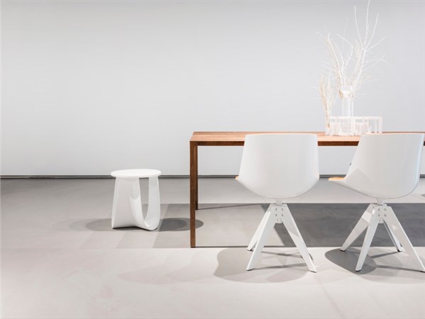 Ambiente minimale con pavimento e parete in resina continua chiara e tavolo bianco