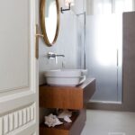 Bagno classico con lavabo d'appoggio su mobile in legno e rivestimento in resina