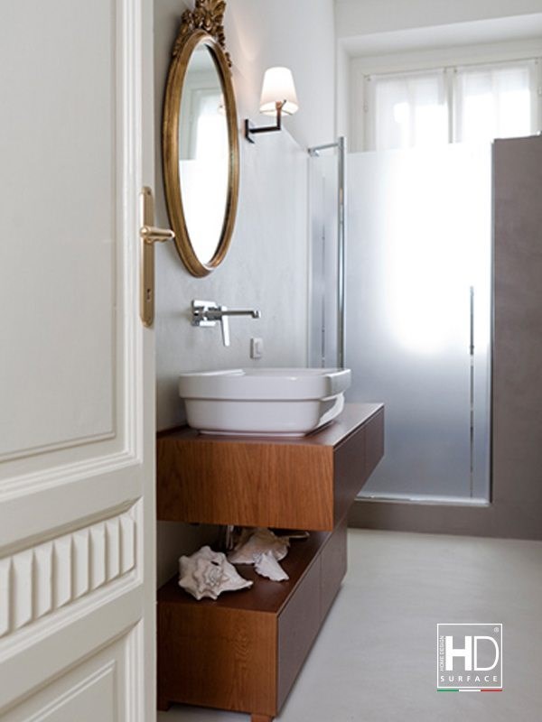 Bagno classico con lavabo d'appoggio su mobile in legno e rivestimento in resina