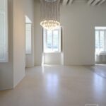 Sala con volte in muratura, pavimento continuo chiaro e lampadario a gocce