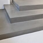 Scala con rivestimento continuo in resina grigia e gradini a sbalzo