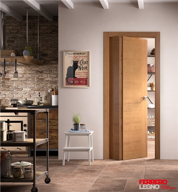 Porta in legno chiaro aperta su una cucina rustica con mattoni a vista