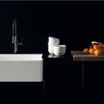 Lavabo bianco rettangolare su piano scuro con miscelatore e frutta