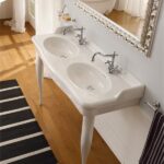 Bagno classico con doppio lavabo su gambe, specchio dorato e pavimento in legno
