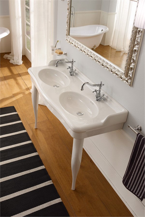 Bagno classico con doppio lavabo su gambe, specchio dorato e pavimento in legno