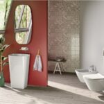 Bagno con parete rossa, lavabo freestanding bianco e sanitari sospesi