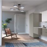Ambiente che unisce bagno e lavanderia con mobili chiari e vetrata sul giardino