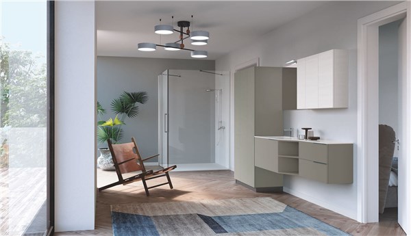 Ambiente che unisce bagno e lavanderia con mobili chiari e vetrata sul giardino