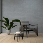 Ambiente minimale con parete effetto cemento, poltrona e pianta