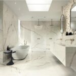 Bagno rivestito in lastre effetto marmo bianco con vasca freestanding e doccia