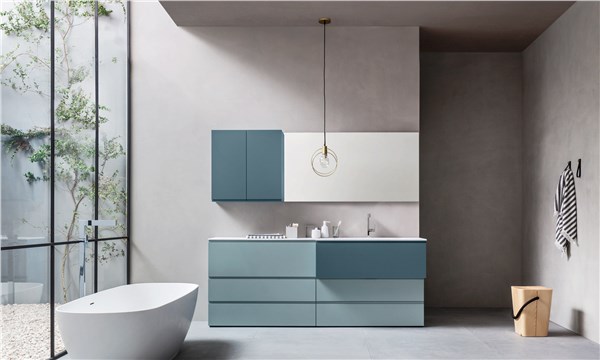 Bagno con mobile azzurro a cassettoni, lavabo integrato e vasca freestanding