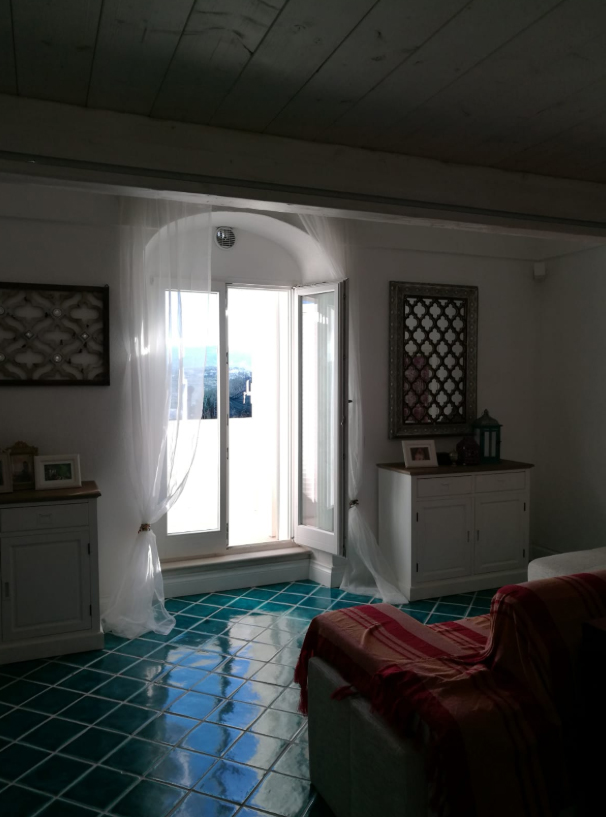 Monolocale con pavimento in cementine verdi, letto e porta finestra
