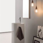 Lavabo freestanding cilindrico chiaro con specchio e lampade a sospensione