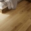 Camera da letto con pavimento in legno rovere naturale e letto con plaid