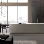 Cucina con isola dal profilo obliquo, vetrata e libreria a parete