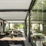 Pergola bioclimatica che copre la sala esterna di un ristorante con tavoli apparecchiati