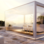 Pergola bioclimatica vetrata illuminata al tramonto su una terrazza
