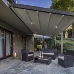 Pergotenda con copertura in tessuto e luci integrate sopra un salotto da giardino