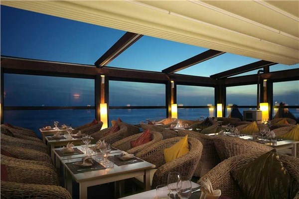 Sala di un ristorante coperta da una pergotenda con vista sul mare al tramonto