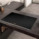 Piano cottura a induzione incassato in un top scuro con utensili e ciotole