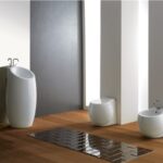 Lavabo a colonna bianco con wc e bidet a terra in un bagno luminoso