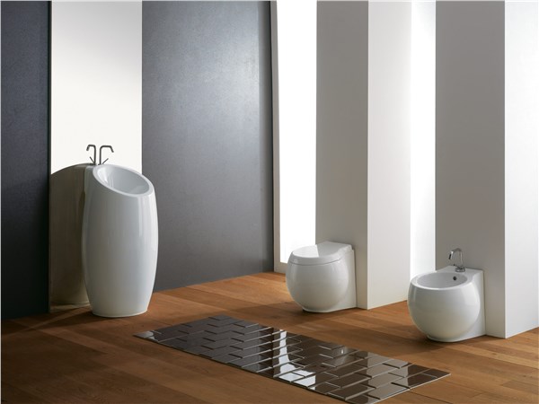 Lavabo a colonna bianco con wc e bidet a terra in un bagno luminoso