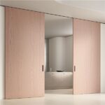 Due porte scorrevoli in legno chiaro a tutta altezza su una parete continua