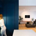 Ambiente con parete blu, zona living e persona che cammina in controluce