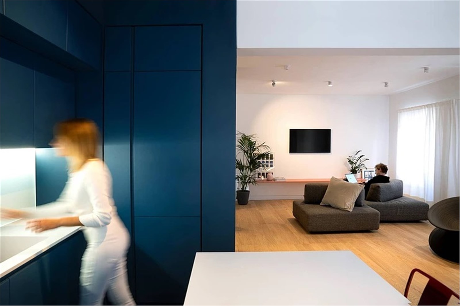 Ambiente con parete blu, zona living e persona che cammina in controluce