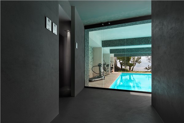 Ambiente con pareti in resina continua affacciato su una piscina interna