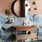 Bagno con rivestimento decorato a motivi blu, consolle in legno e specchio tondo